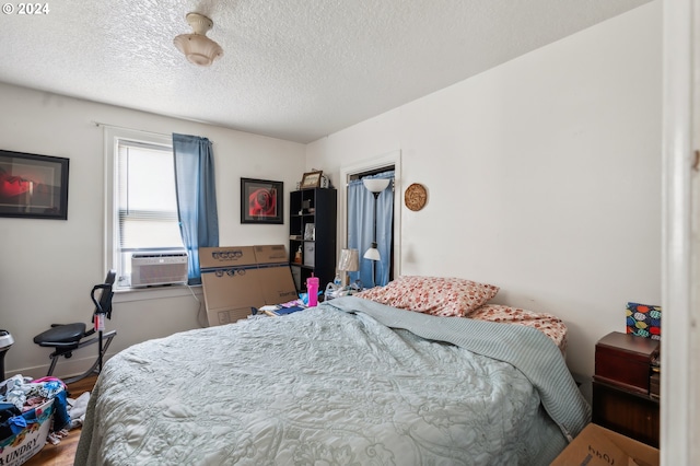 bedroom with hardwood / wood-style floors, cooling unit, and a textured ceiling