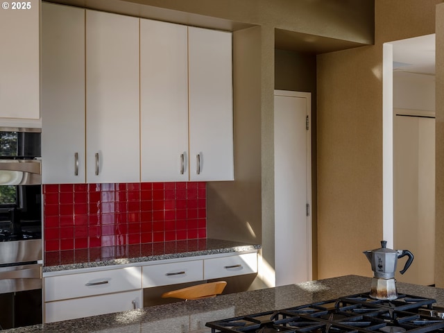 3342 SW Fairmount Blvd, Portland, OR 97239 - kitchen featuring backsplash, white cabinetry, dark stone counters, and gas cooktop