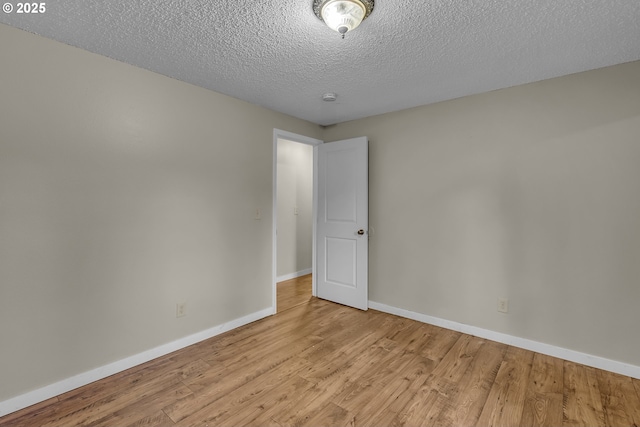 unfurnished room with baseboards, a textured ceiling, and light wood finished floors