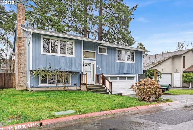 split foyer home with a garage, a chimney, and a front yard