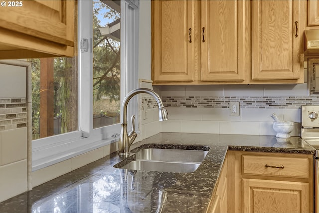 interior details with light brown cabinets, backsplash, dark stone countertops, and a sink