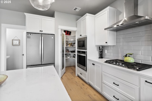 3588 Nestucca Loop, Eugene, OR 97408 - kitchen featuring stainless steel appliances, wall chimney exhaust hood, white cabinets, and tasteful backsplash
