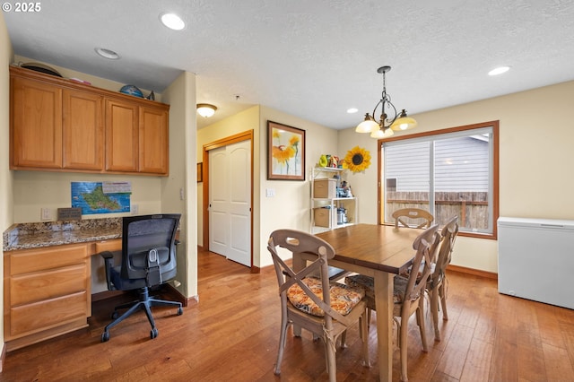 dining space with an inviting chandelier, a textured ceiling, baseboards, and hardwood / wood-style floors