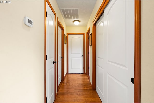 hallway featuring a textured ceiling, visible vents, and wood finished floors