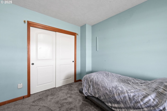 bedroom featuring carpet, a closet, a textured ceiling, and baseboards