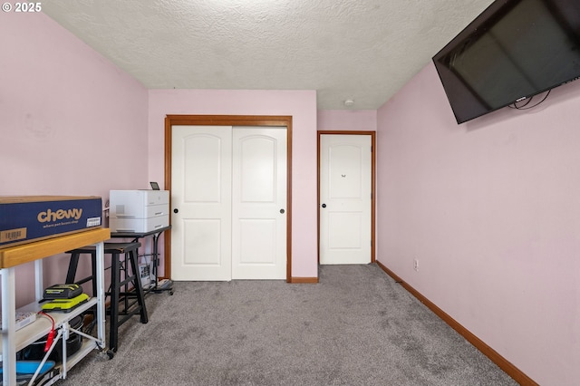 carpeted bedroom featuring a textured ceiling, baseboards, and a closet