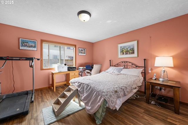 bedroom featuring a textured ceiling, baseboards, and wood finished floors