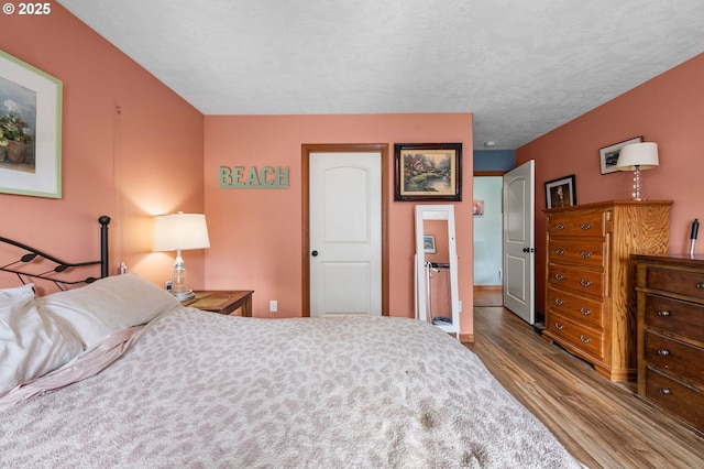 bedroom with a textured ceiling and wood finished floors