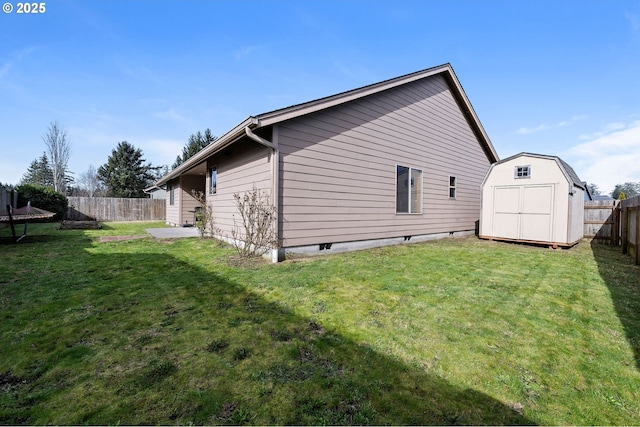 view of side of home with a yard, a fenced backyard, a storage unit, and an outbuilding