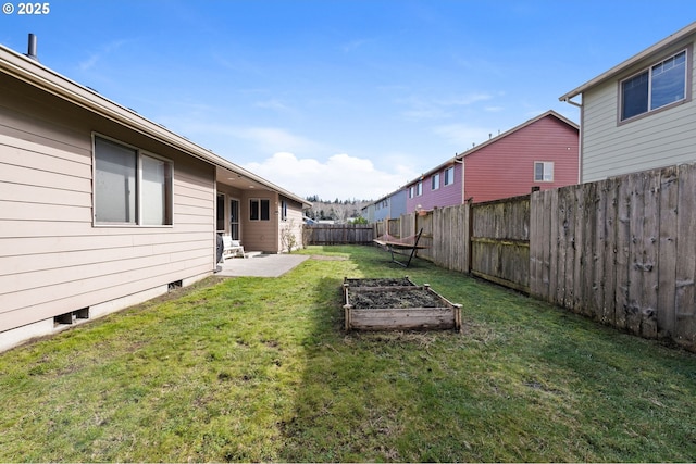 view of yard featuring a vegetable garden, a fenced backyard, and a patio