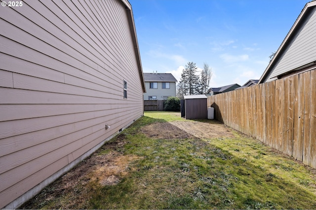 view of yard featuring a fenced backyard, a storage unit, and an outbuilding