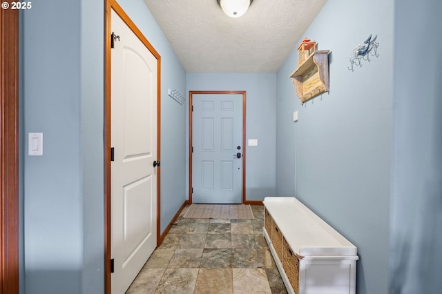 doorway to outside featuring stone finish flooring, baseboards, and a textured ceiling