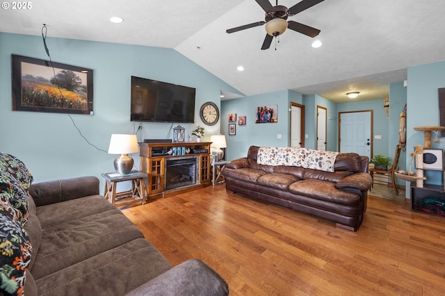 living room with ceiling fan, recessed lighting, wood finished floors, vaulted ceiling, and a glass covered fireplace