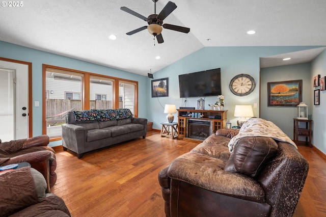 living room with a fireplace, wood-type flooring, vaulted ceiling, a textured ceiling, and ceiling fan