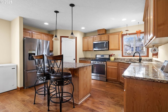 kitchen with a center island, a breakfast bar, dark wood finished floors, stainless steel appliances, and a sink