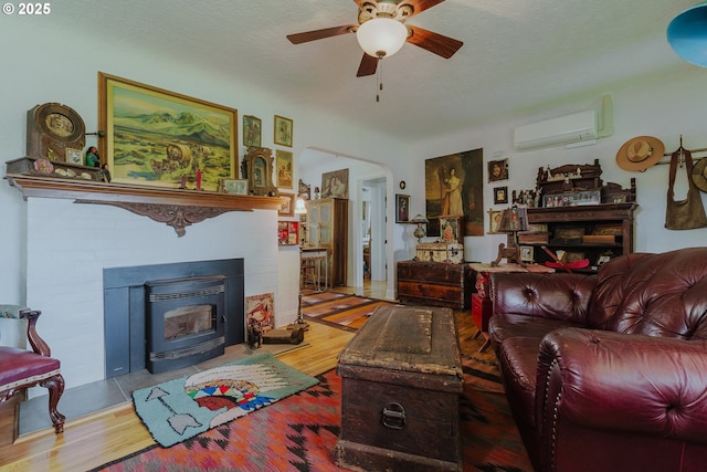 2112 Salem Ave, Albany, OR 97321 - living room featuring a wall mounted AC, a ceiling fan, wood finished floors, and a fireplace with flush hearth