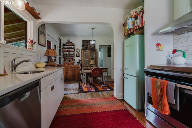 2112 Salem Ave, Albany, OR 97321 - kitchen featuring appliances with stainless steel finishes, a sink, wall chimney exhaust hood, wood finished floors, and tasteful backsplash