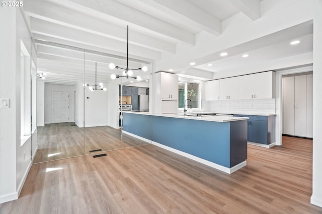 570 N Hayden Bay Dr, Portland, OR 97217 - kitchen featuring beamed ceiling, white cabinets, recessed lighting, decorative backsplash, and light wood finished floors