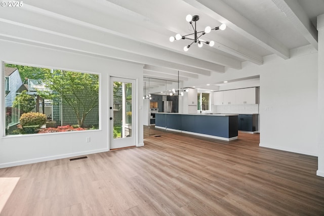 570 N Hayden Bay Dr, Portland, OR 97217 - unfurnished living room featuring a chandelier, plenty of natural light, light wood-style flooring, and beam ceiling