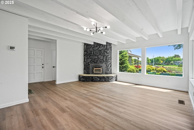 570 N Hayden Bay Dr, Portland, OR 97217 - unfurnished living room with beamed ceiling, a chandelier, baseboards, wood finished floors, and a stone fireplace