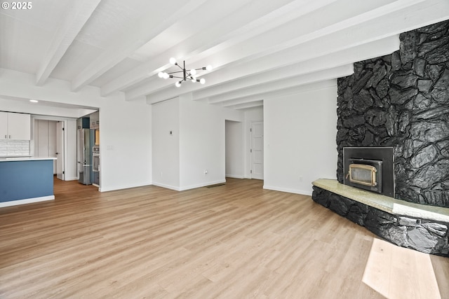 570 N Hayden Bay Dr, Portland, OR 97217 - unfurnished living room featuring light wood-style flooring, beam ceiling, baseboards, a wood stove, and a chandelier