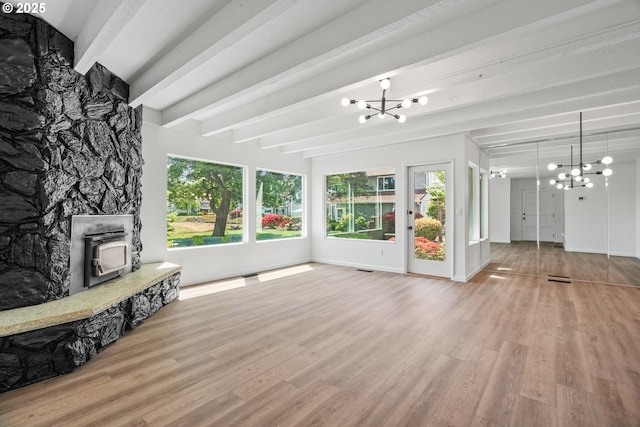 570 N Hayden Bay Dr, Portland, OR 97217 - unfurnished living room with a chandelier, beam ceiling, wood finished floors, a wood stove, and baseboards