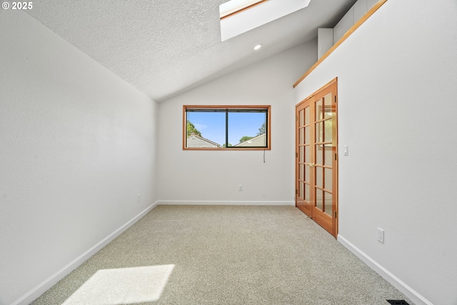 570 N Hayden Bay Dr, Portland, OR 97217 - spare room with vaulted ceiling, a skylight, light colored carpet, baseboards, and a textured ceiling