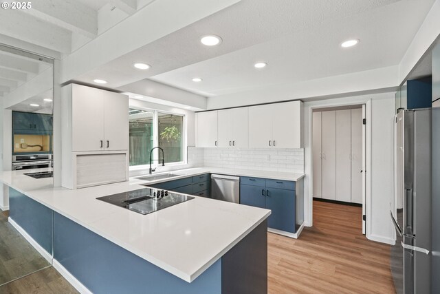 570 N Hayden Bay Dr, Portland, OR 97217 - kitchen featuring appliances with stainless steel finishes, a sink, light wood-style flooring, a peninsula, and recessed lighting