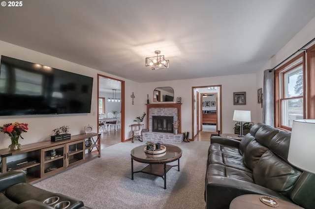 living area with an inviting chandelier, a brick fireplace, and carpet flooring