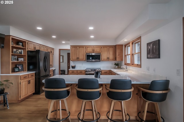 kitchen with appliances with stainless steel finishes, light countertops, a sink, and a breakfast bar area