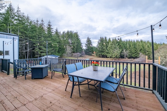 wooden terrace featuring outdoor dining space, an outbuilding, and a storage unit