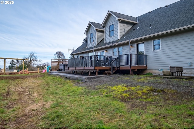 back of house featuring a shingled roof, a yard, and a wooden deck