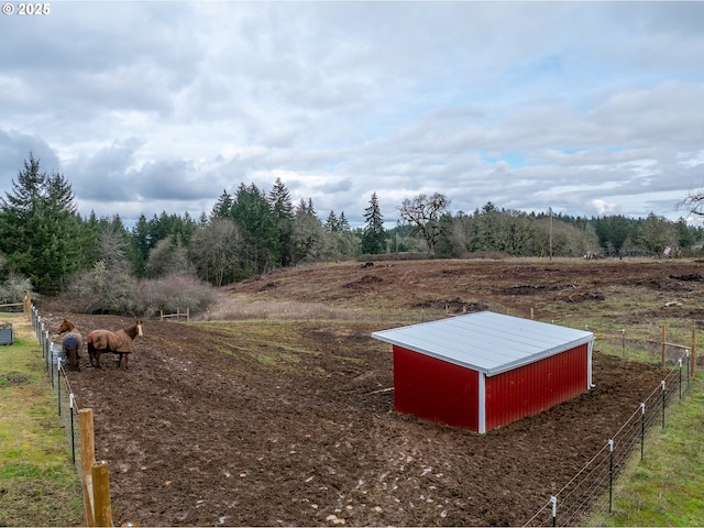 view of yard featuring a pole building, fence, an outbuilding, and a rural view