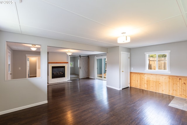 207 N Maple St, Bingen, WA 98605 - unfurnished living room featuring a barn door, dark wood finished floors, a wainscoted wall, and wooden walls