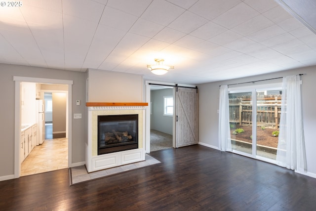207 N Maple St, Bingen, WA 98605 - unfurnished living room with baseboards, a glass covered fireplace, a barn door, and wood finished floors