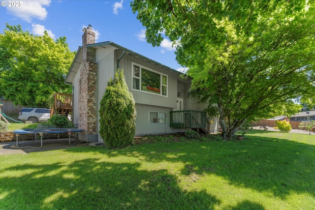 22165 SE Mark Rd, Damascus, OR 97089 - back of house with a trampoline, a chimney, a lawn, and a deck