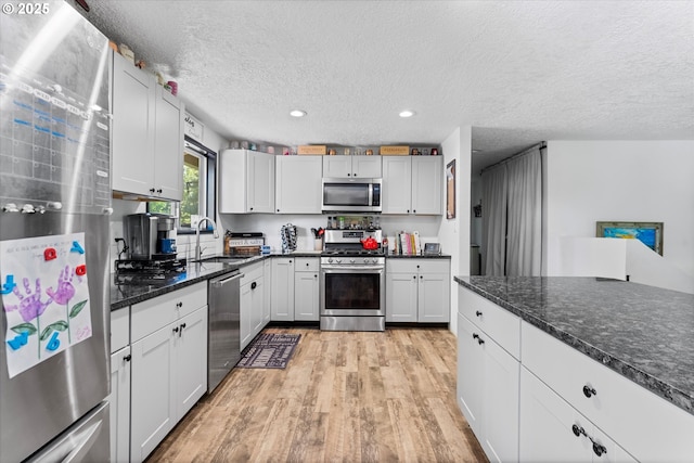 22165 SE Mark Rd, Damascus, OR 97089 - kitchen with appliances with stainless steel finishes, a sink, light wood finished floors, a textured ceiling, and recessed lighting