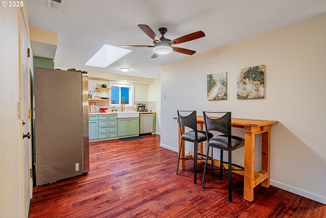 kitchen with visible vents, dark wood-type flooring, a sink, stainless steel appliances, and green cabinets