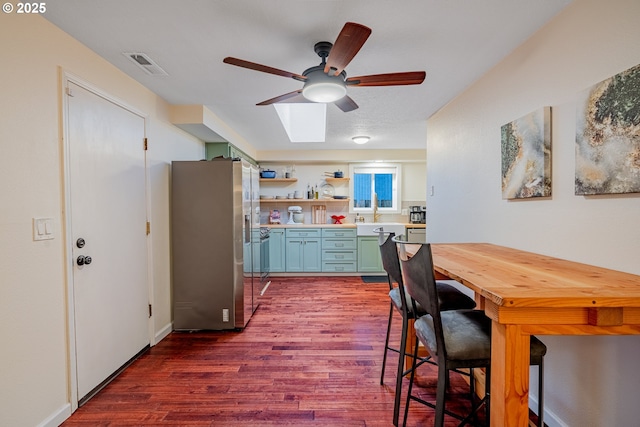 kitchen with visible vents, dark wood-style floors, stainless steel fridge with ice dispenser, and light countertops