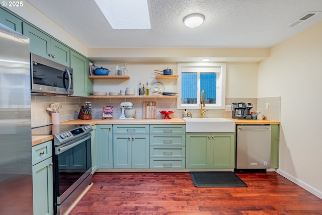 kitchen featuring green cabinets, visible vents, appliances with stainless steel finishes, and a sink