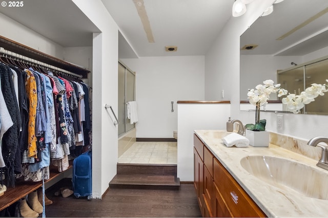 19065 Trillium Dr, West Linn, OR 97068 - bathroom featuring a shower with shower door, double vanity, wood finished floors, and a walk in closet