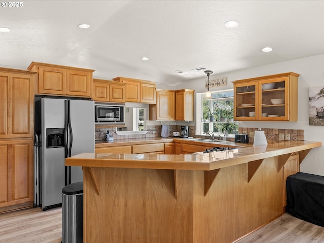 6759 Jasmine Ct, Brookings, OR 97415 - kitchen with a breakfast bar, backsplash, glass insert cabinets, and appliances with stainless steel finishes