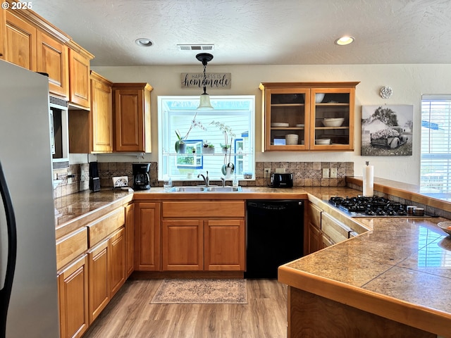 6759 Jasmine Ct, Brookings, OR 97415 - kitchen featuring light wood-style flooring, visible vents, a sink, tile counters, and appliances with stainless steel finishes