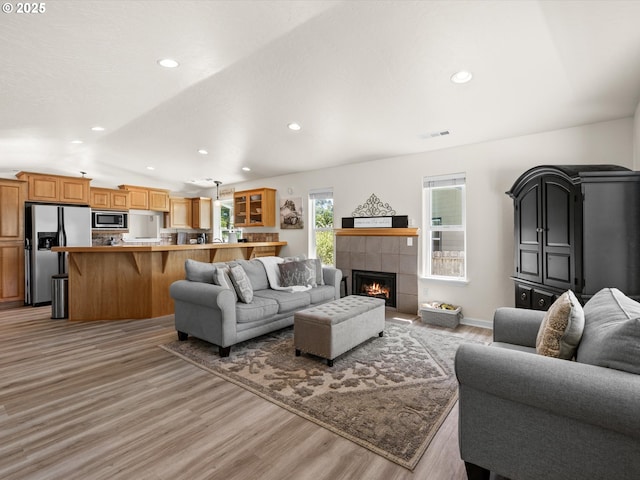 6759 Jasmine Ct, Brookings, OR 97415 - living area featuring recessed lighting, a tiled fireplace, visible vents, vaulted ceiling, and light wood-style floors