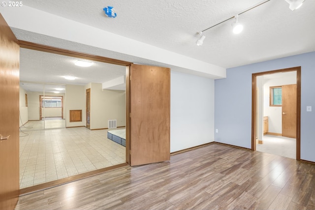 14428 NE Failing St, Portland, OR 97230 - empty room featuring wood finished floors, a textured ceiling, and track lighting