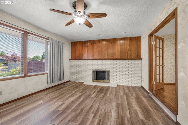 14428 NE Failing St, Portland, OR 97230 - unfurnished living room with wood finished floors, a textured ceiling, ceiling fan, and a fireplace