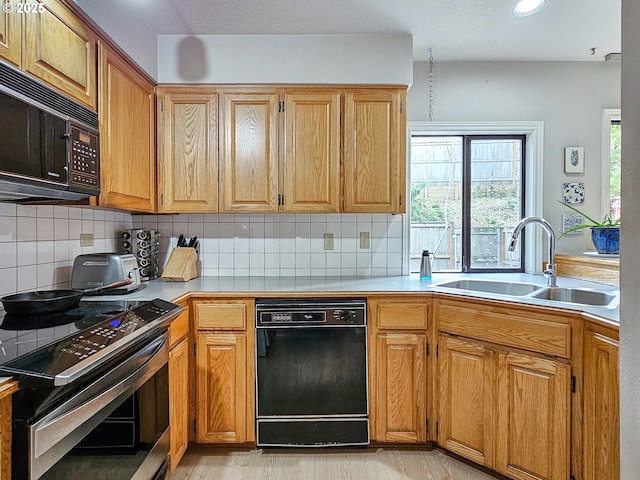 kitchen with light countertops, electric range, backsplash, a sink, and black microwave