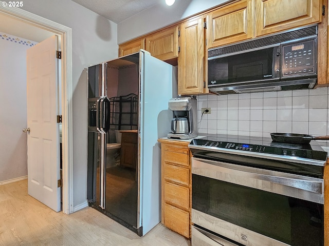 kitchen with backsplash, baseboards, light wood finished floors, and black appliances