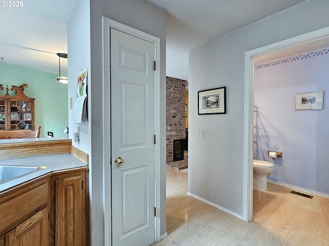 bathroom featuring baseboards, visible vents, toilet, wood finished floors, and vanity