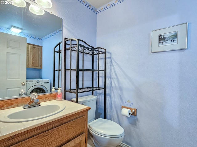 half bathroom featuring toilet, a textured wall, washer / clothes dryer, and vanity